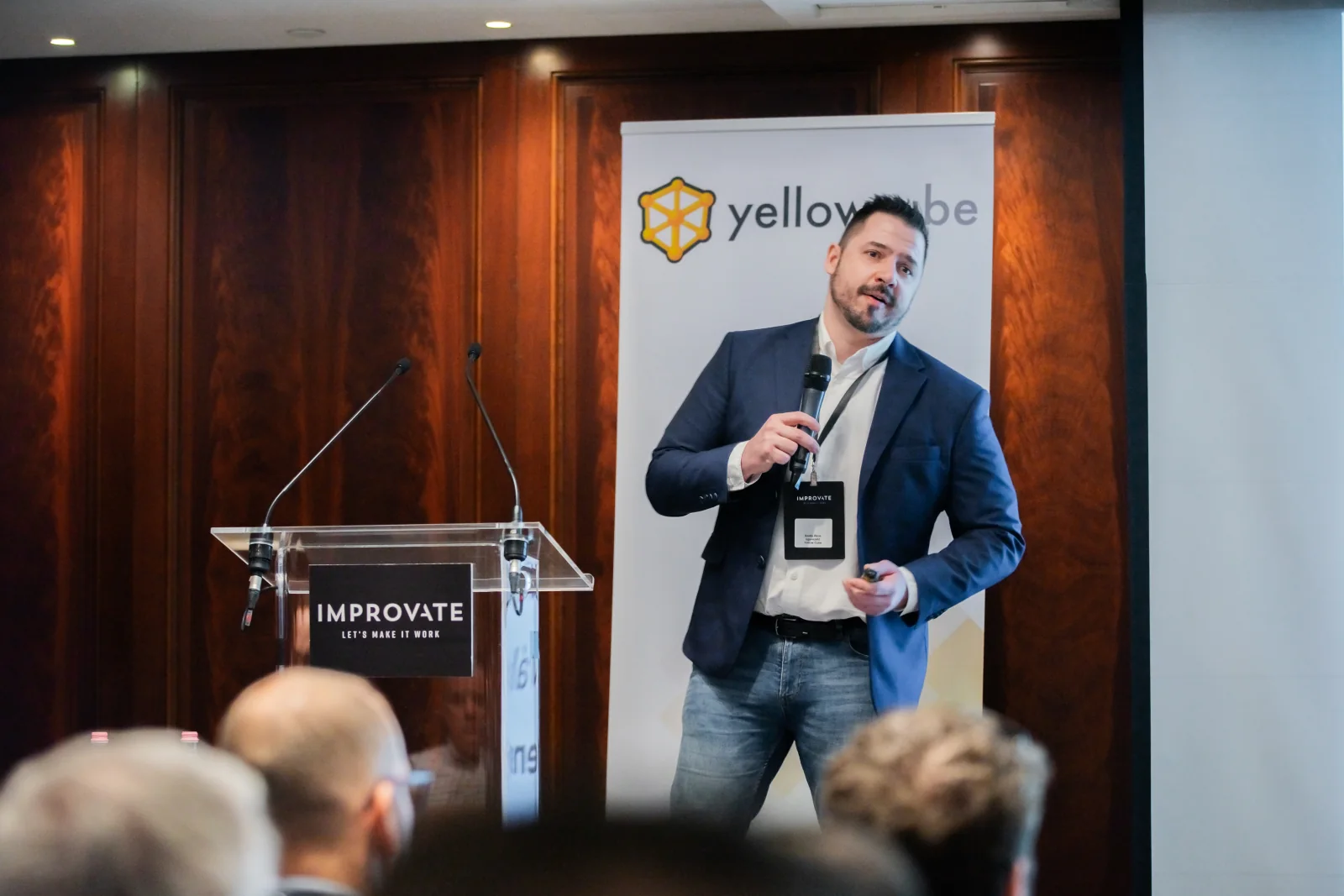 Egy előadó egy Yellow Cube-molinó előtt beszél