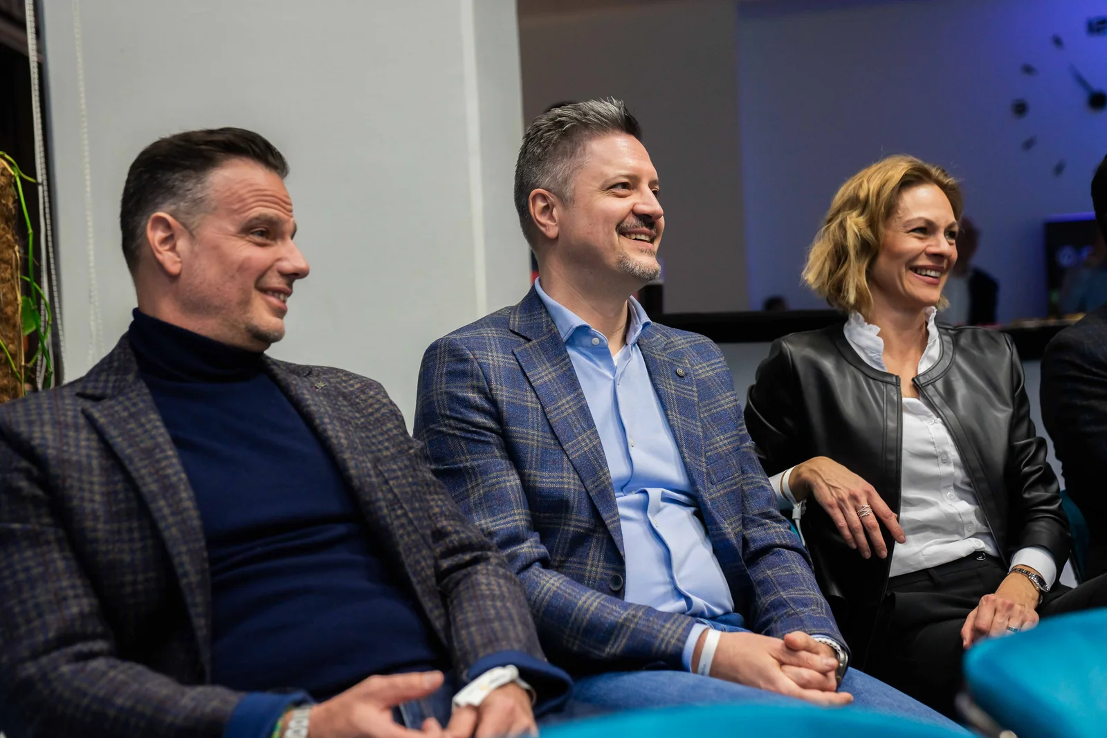 Three attendees smile while watching a presentation.