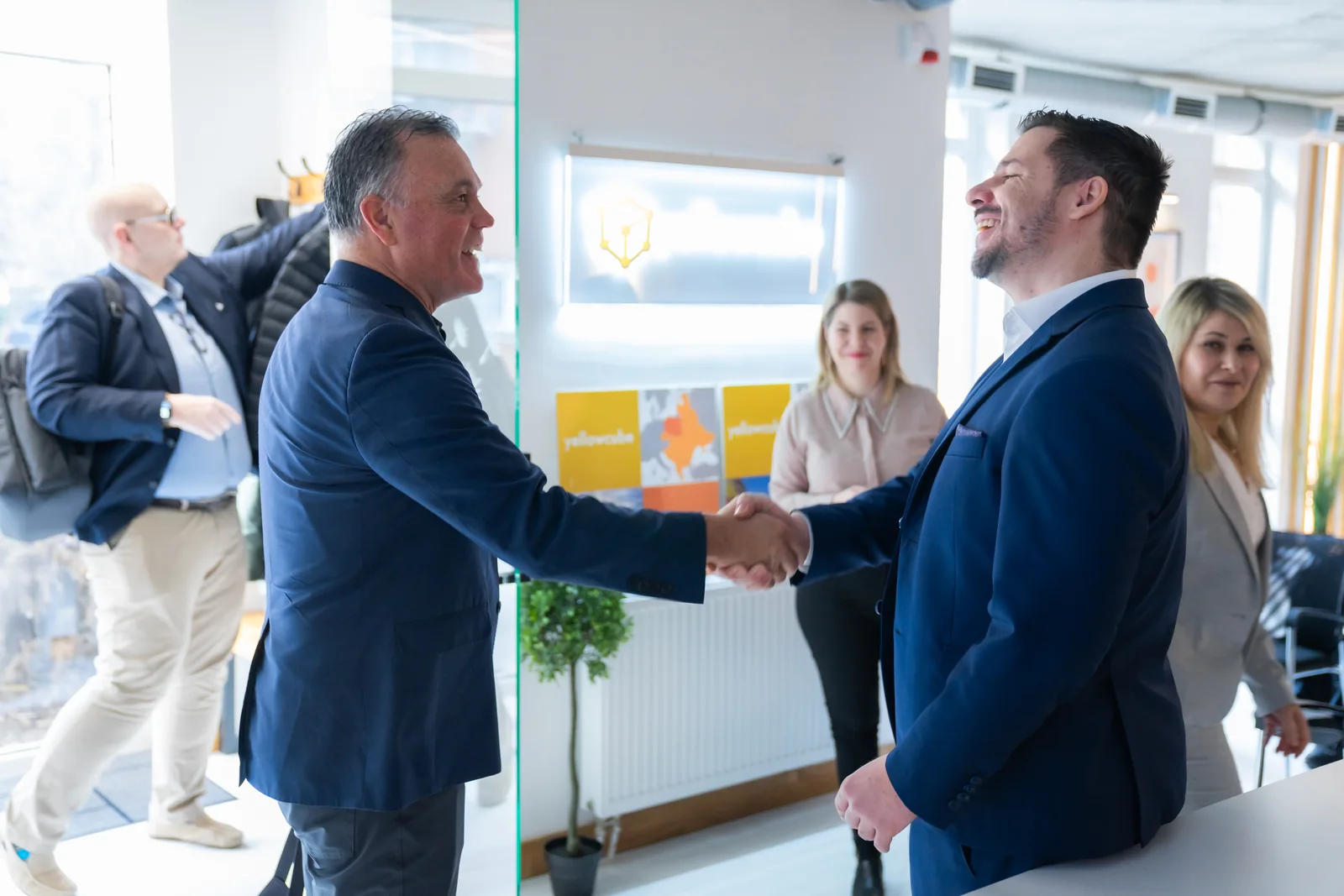 Two people shake hands and smile in the Yellow Cube workspace.